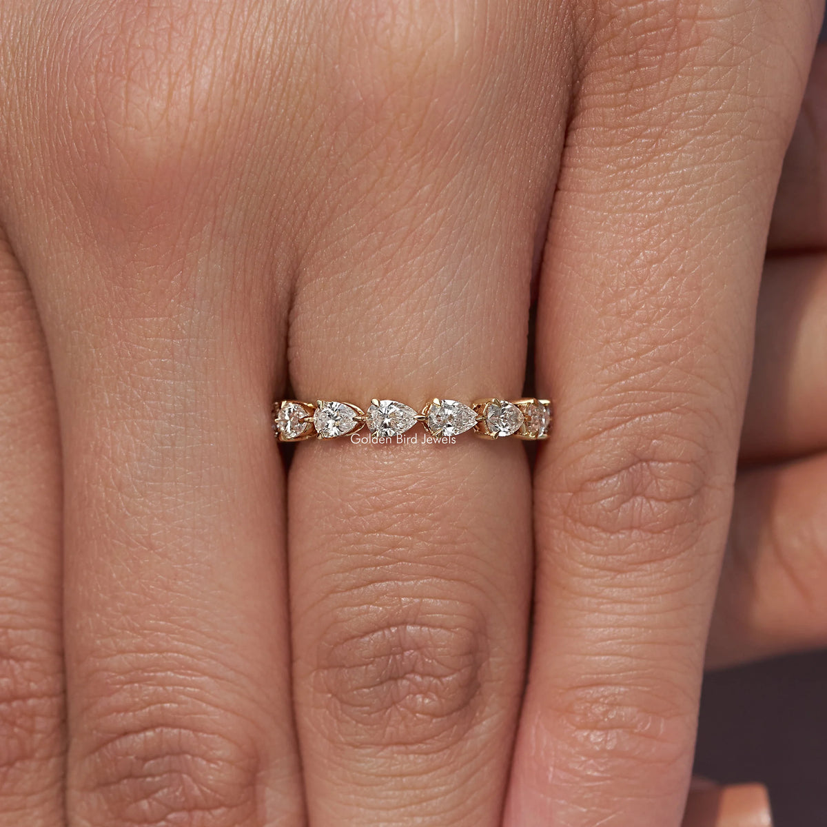 Pear-shaped stone eternity band ring with thin gold band on fingers