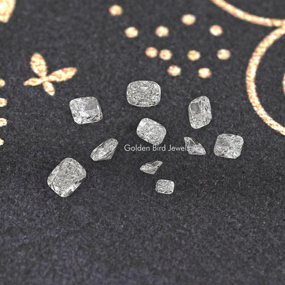 Loose lab-grown elongated cushion diamonds in assorted sizes, scattered on dark display felt.