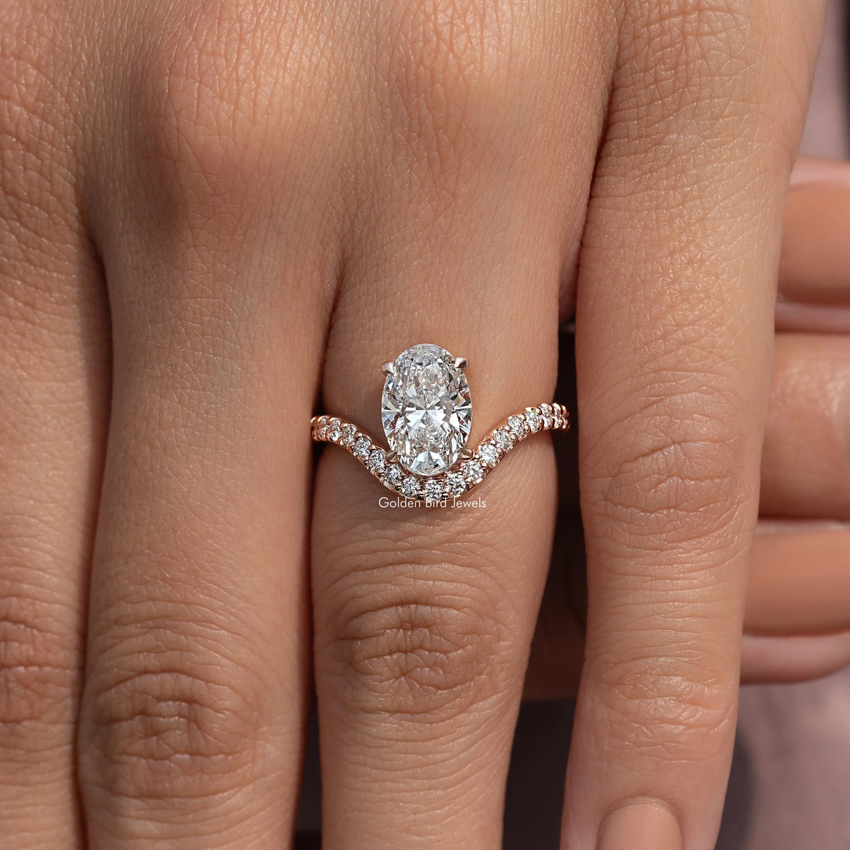 Oval-cut lab diamond ring with curved pavé accent band on finger