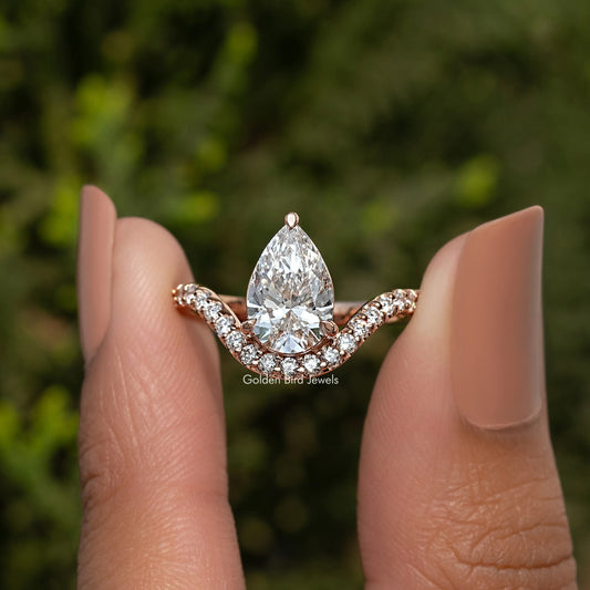 Pear-cut center stone with curved halo accents on an engagement ring band