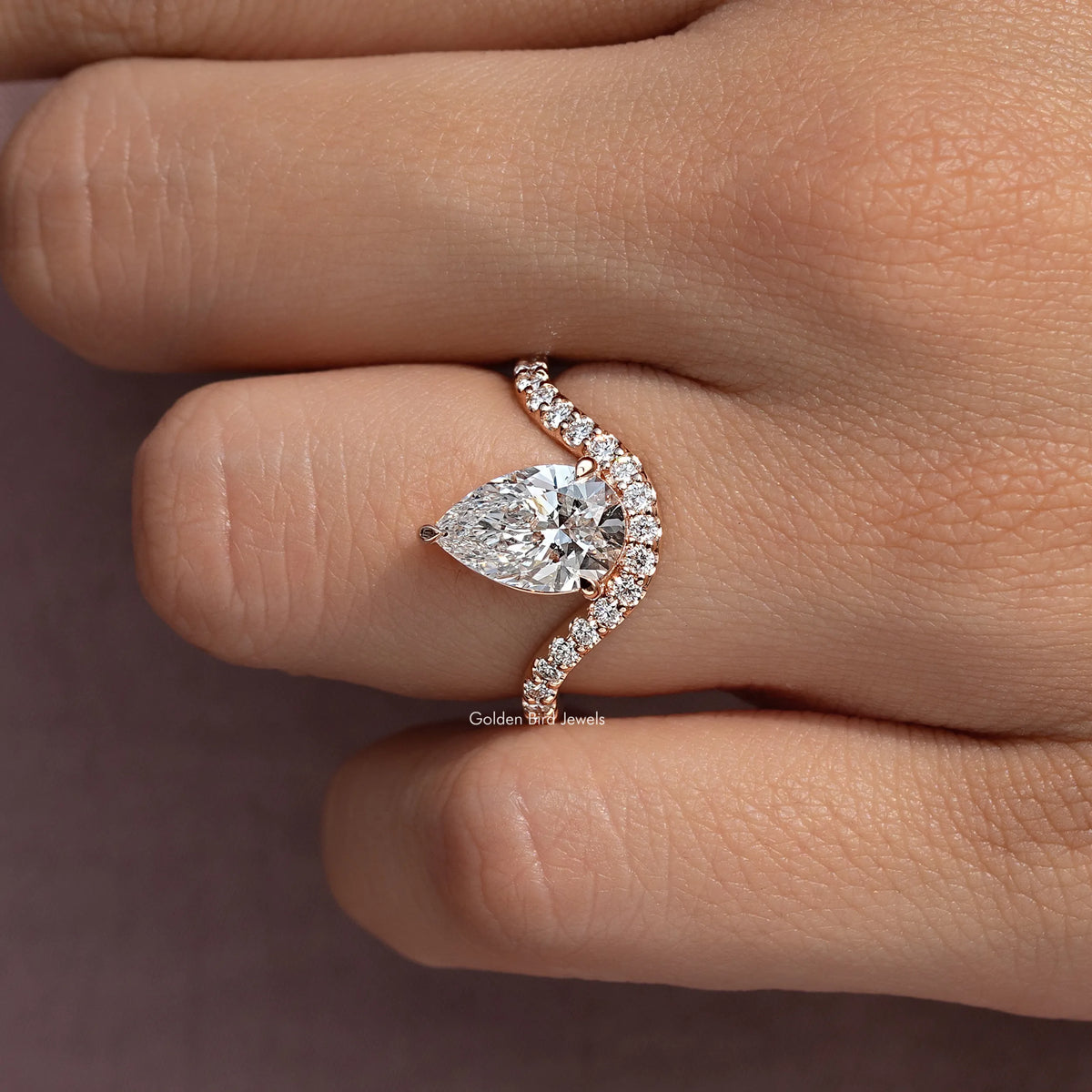 Pear-cut engagement ring with curved pave band and pear-shaped center stone