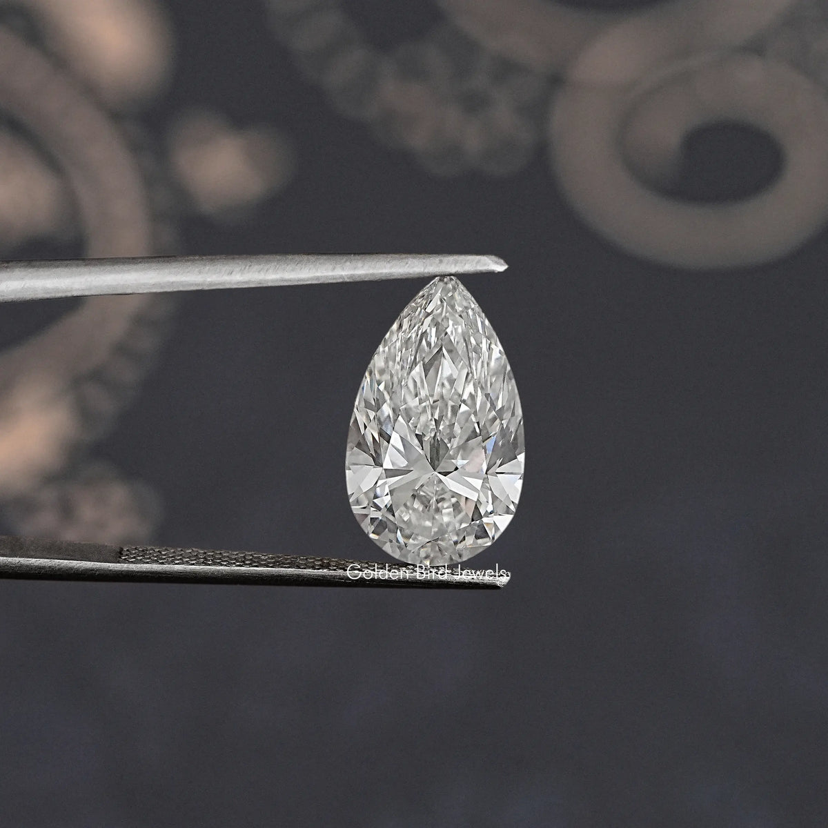 Face-up loose pear-cut lab diamond between metal tweezers, clear white sparkle.