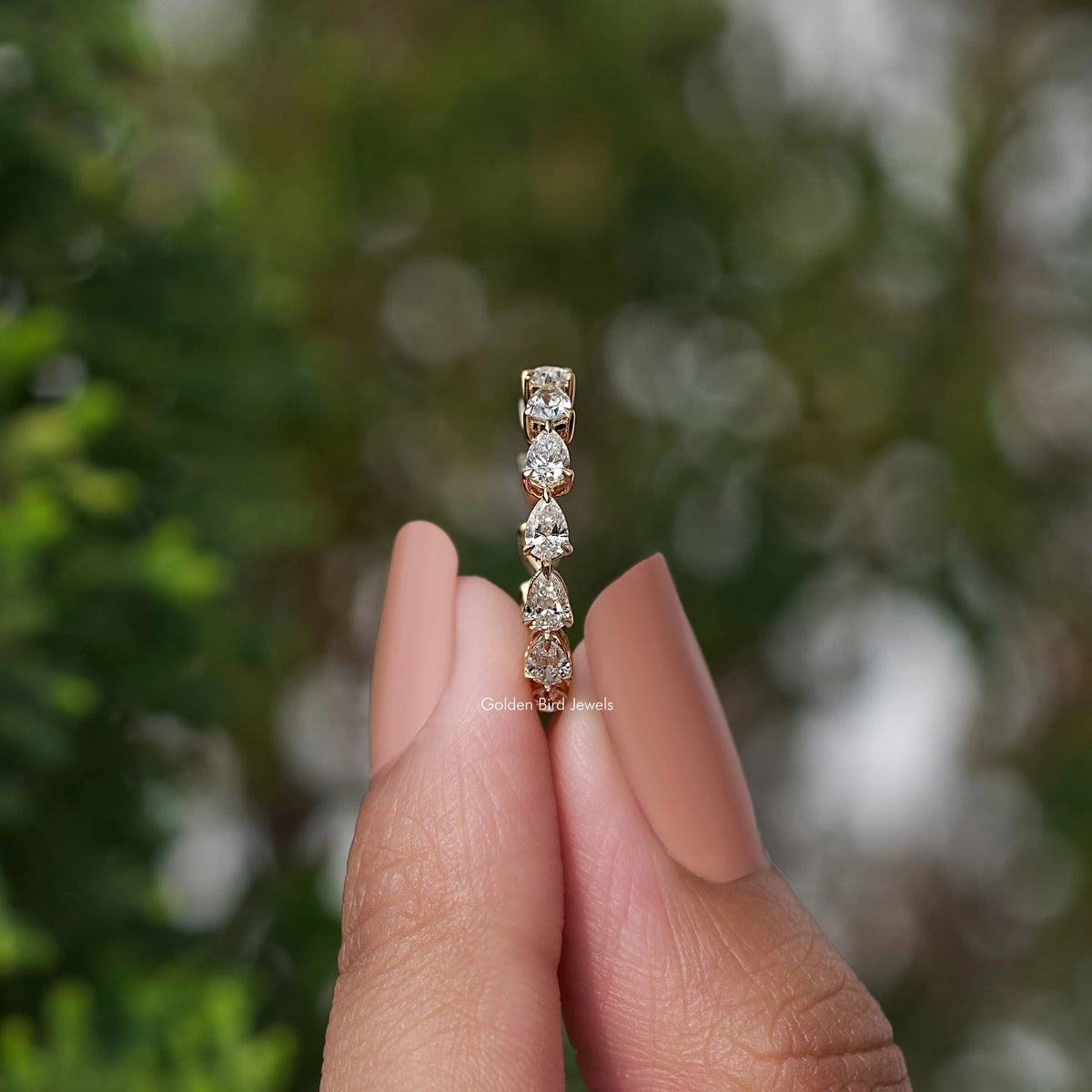 Gold lab-grown diamond pear-shaped eternity wedding band ring on hand
