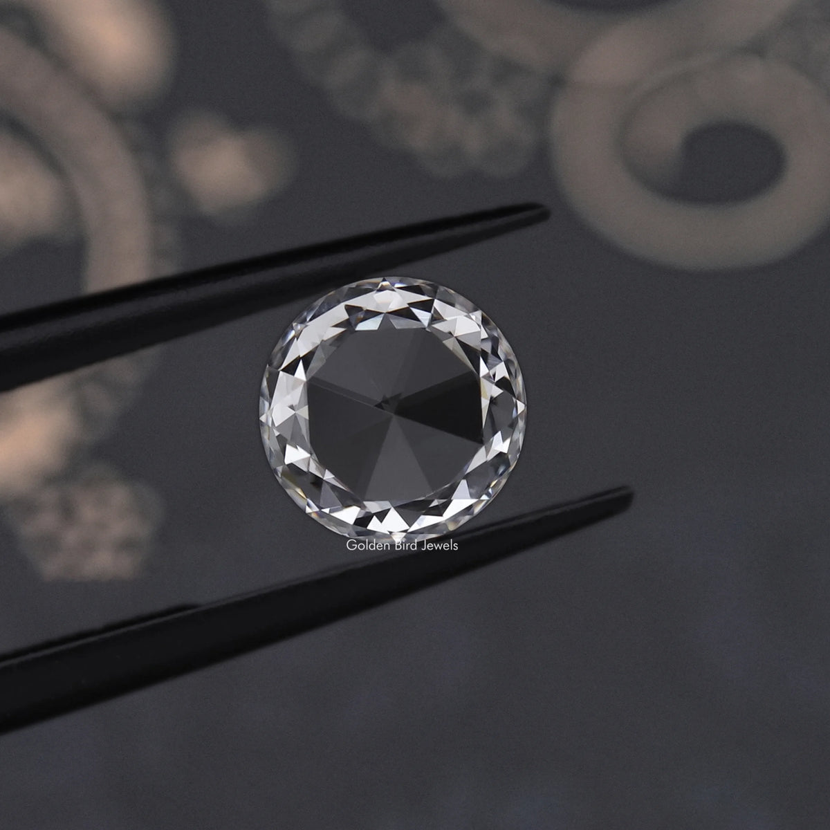 Round rose-cut lab-grown diamond on dark surface, shown between two black prongs