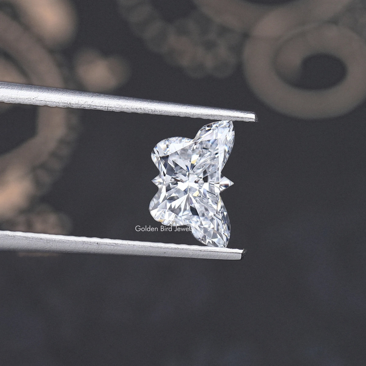 Butterfly-cut lab-grown diamond in tweezers, side view of bright facets