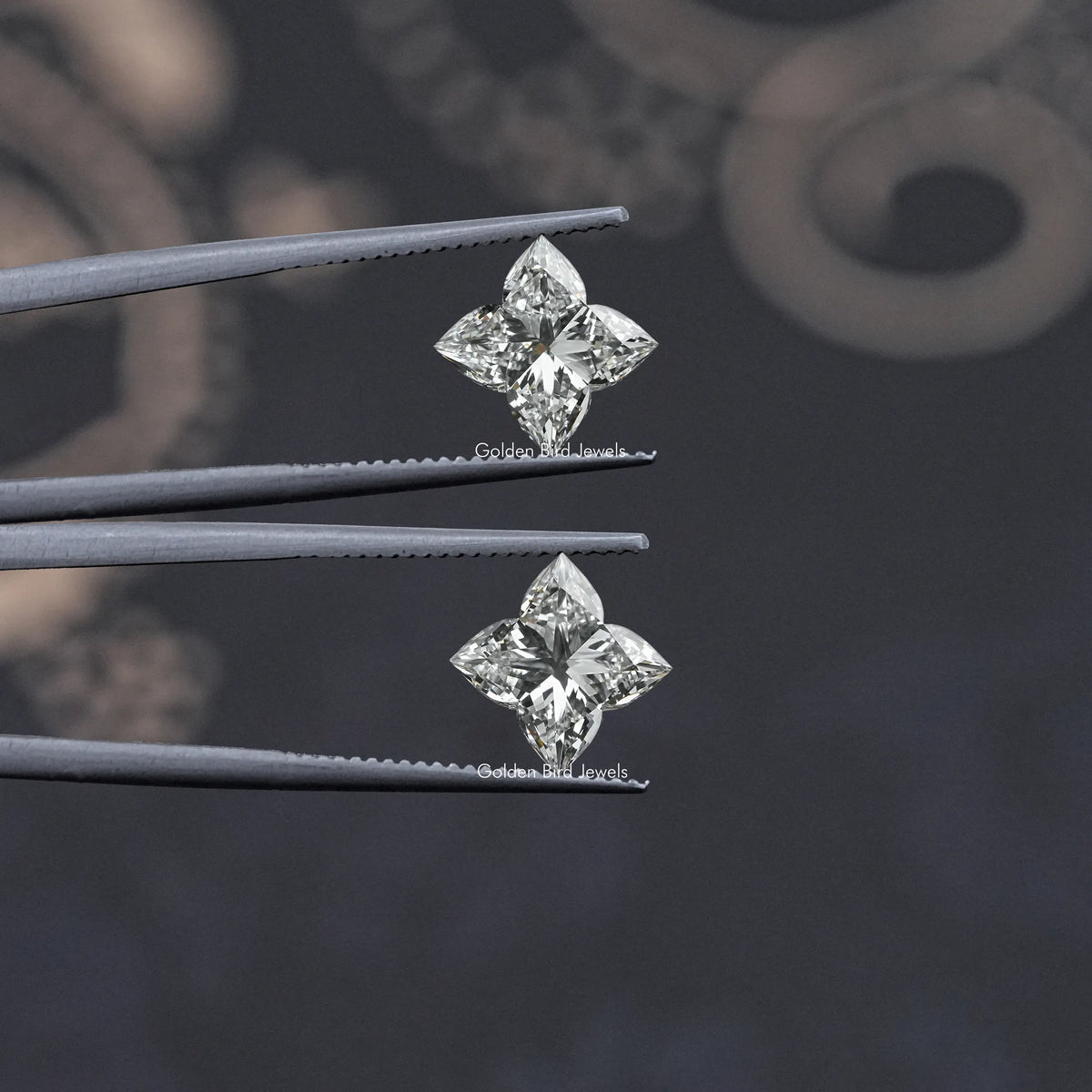 Flower-cut lab-grown diamond studs on tweezers, angled view of two stones
