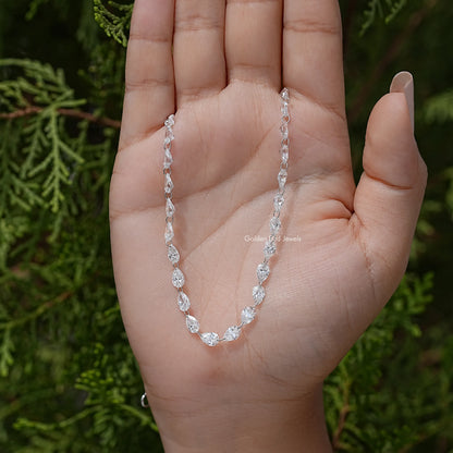 Silver pear-cut diamond tennis necklace across palm, oval link stations