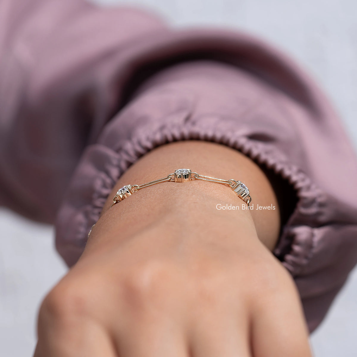 Gold-tone moissanite link bracelet with round-cut stones, arched on wrist