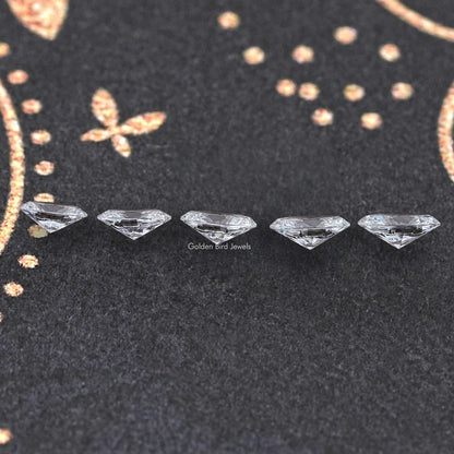 Oval-cut loose lab diamond stones, faceted display on dark textured surface