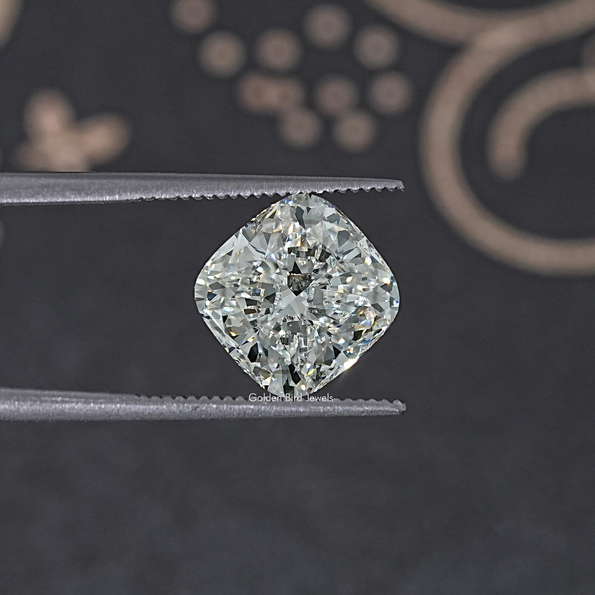 Loose cushion-cut lab diamond on metal tweezers, close-up of sparkling facets