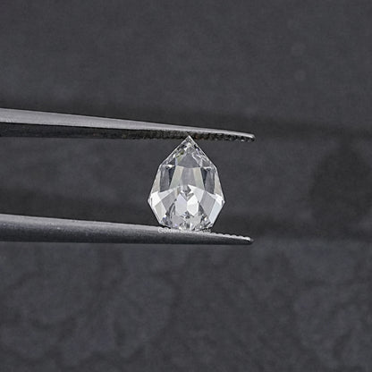 Lab-grown pear-cut diamond held between metal tweezer tips, step-cut facets