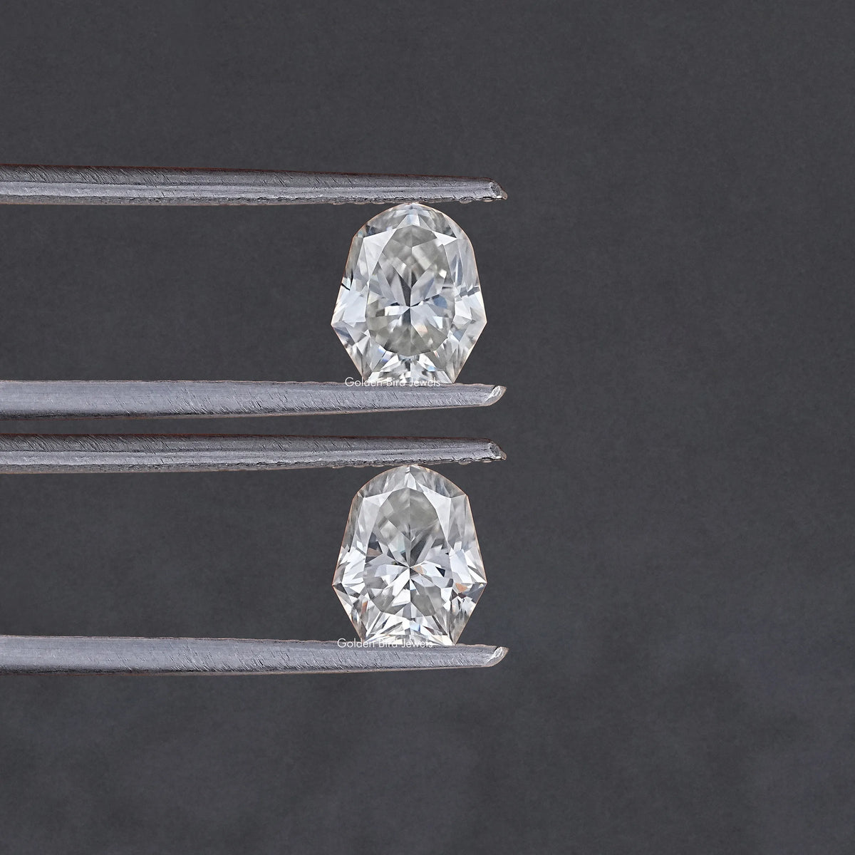 Two shield-cut moissanite stones shown with metal prongs, top and bottom