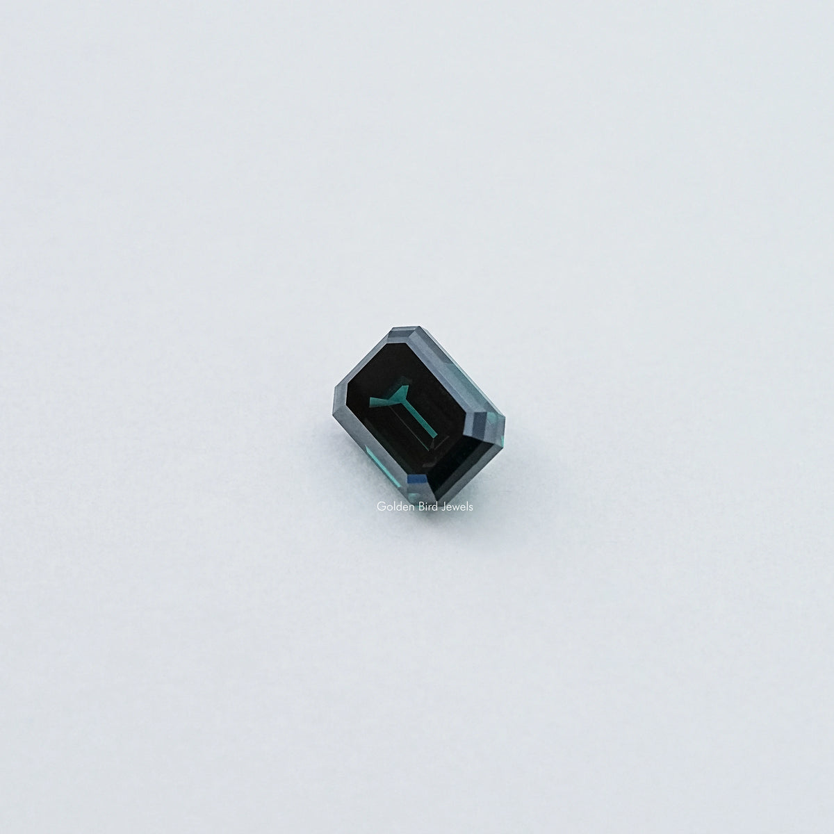 Loose emerald-cut dark green moissanite gemstone, small angled view