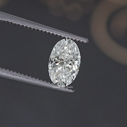 Oval clear moissanite gemstone with crisp facets between gray tweezers