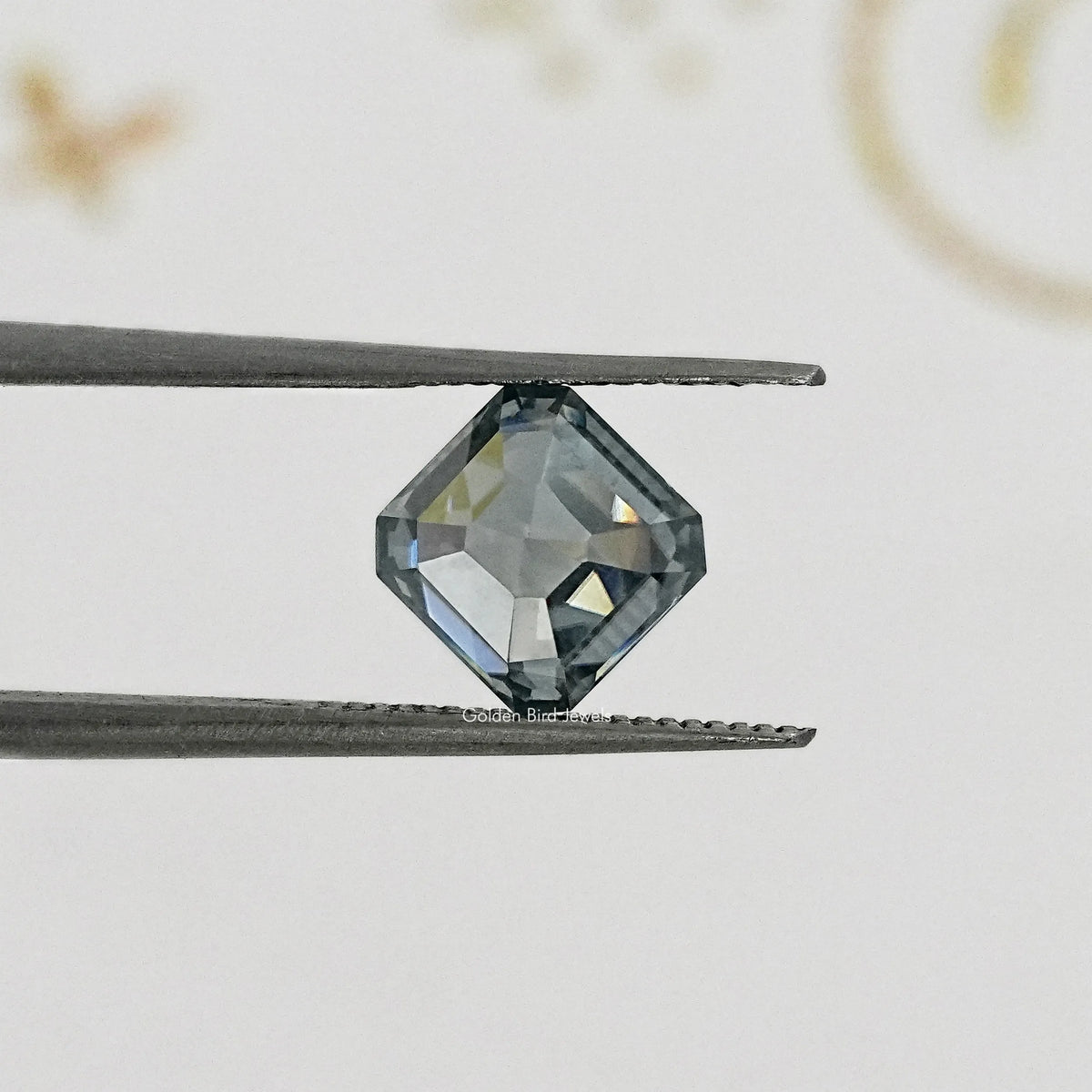Gray Asscher-cut moissanite gemstone on tweezers, side angle close-up