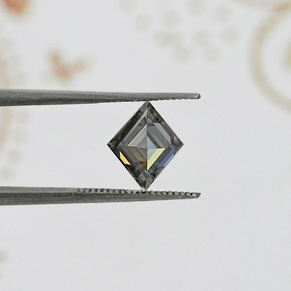 Gray moissanite lozenge shape with step facets, close-up.
