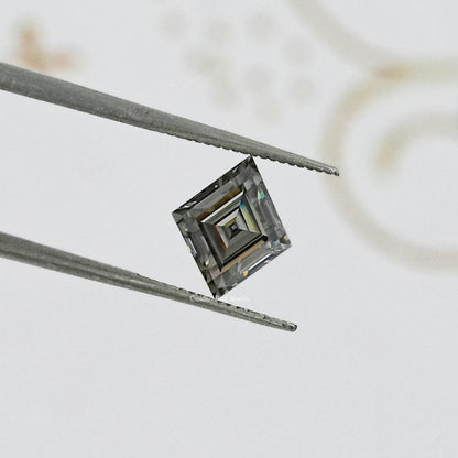 Gray lozenge-cut moissanite with step facets, held between metal tweezers.