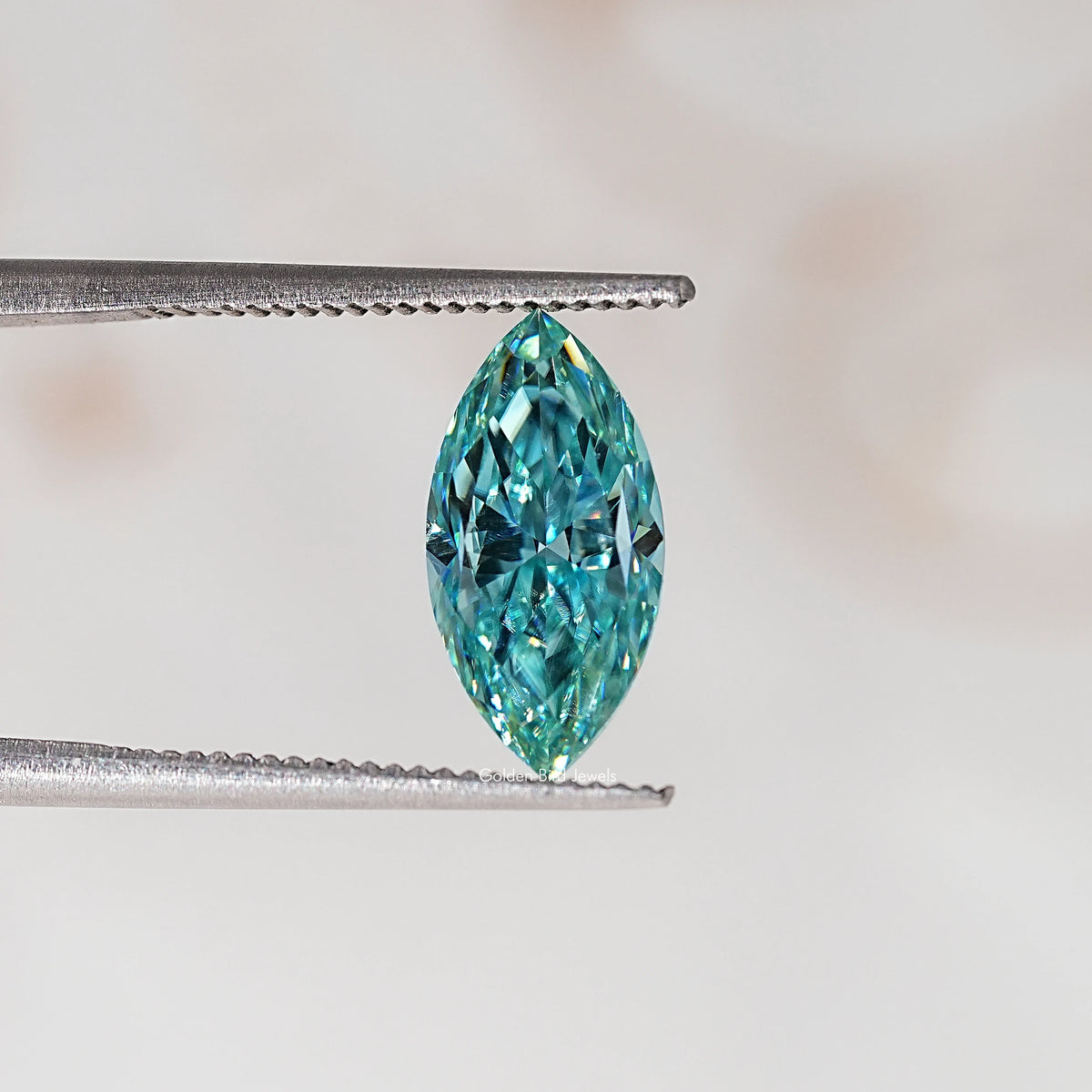 Blue-green marquise-cut moissanite gemstone held in metal tweezers