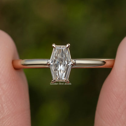 Close-up of gold-tone solitaire ring with prong-set baguette-cut moissanite center