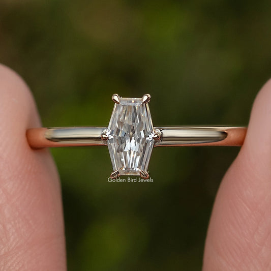 Close-up of gold-tone solitaire ring with prong-set baguette-cut moissanite center