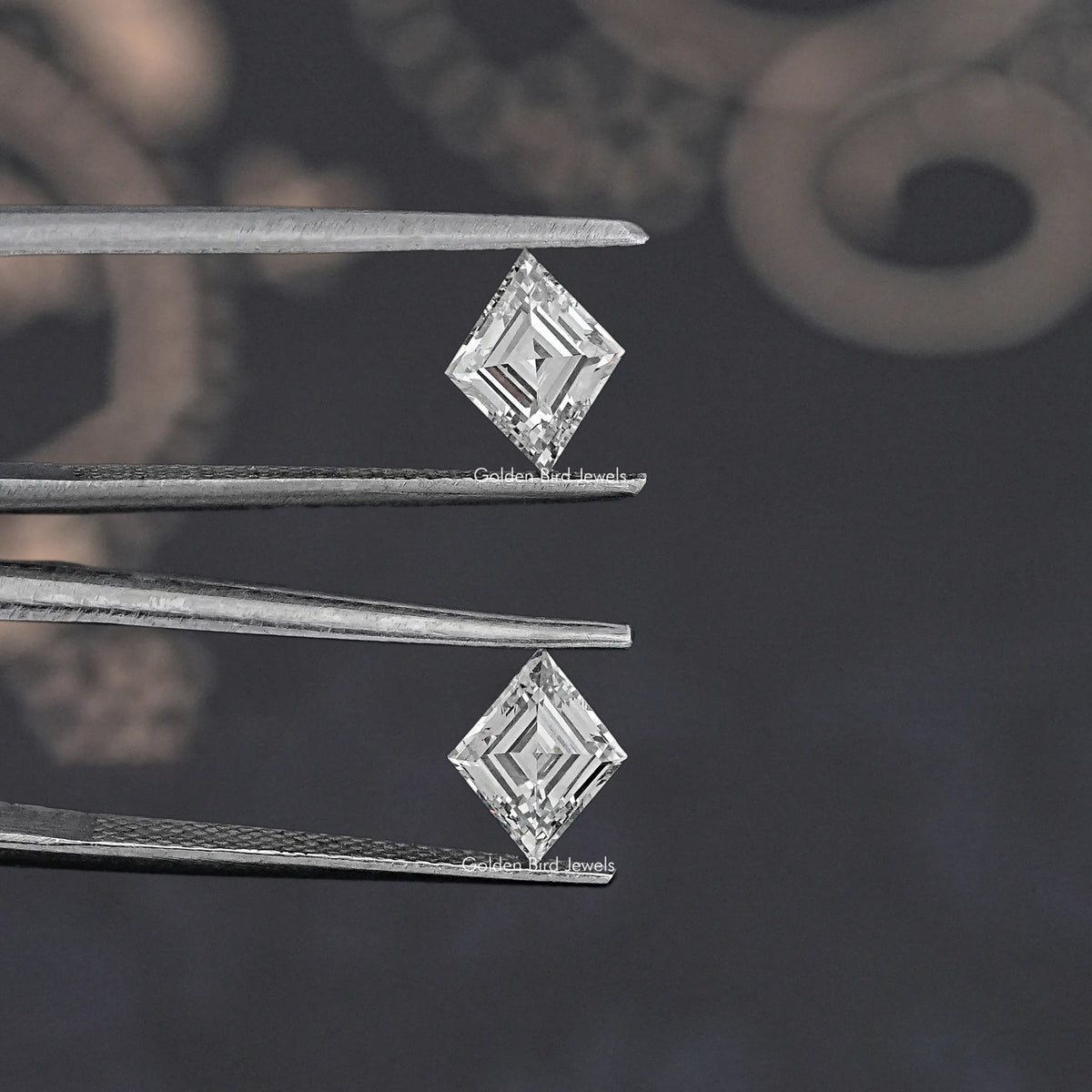 Lozenge-cut lab-grown diamond pair held between metal tweezers, angled view.