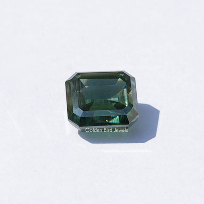 Green emerald-cut loose moissanite gemstone, dark green step-cut facets