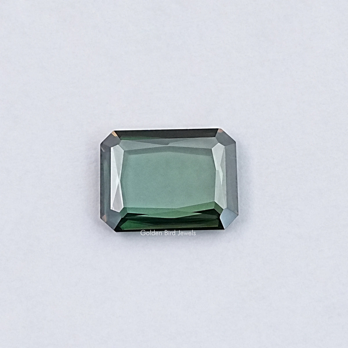Emerald-cut green moissanite loose gemstone with sharp step facets, rectangular shape