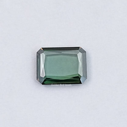 Emerald-cut green moissanite loose gemstone with sharp step facets, rectangular shape