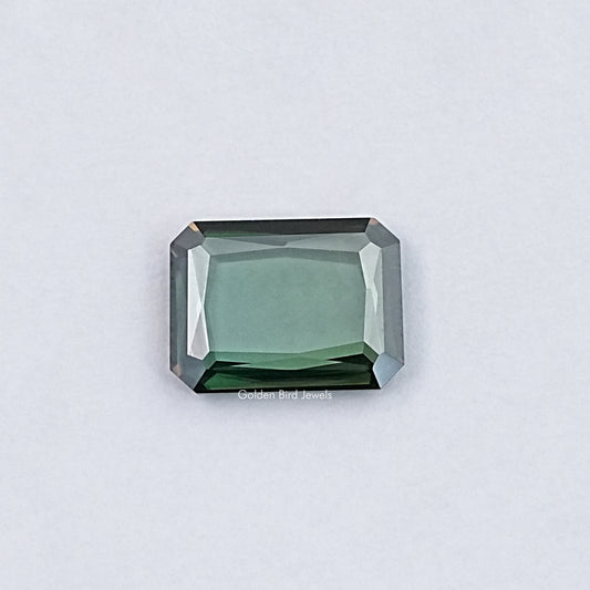 Emerald-cut green moissanite loose gemstone with sharp step facets, rectangular shape