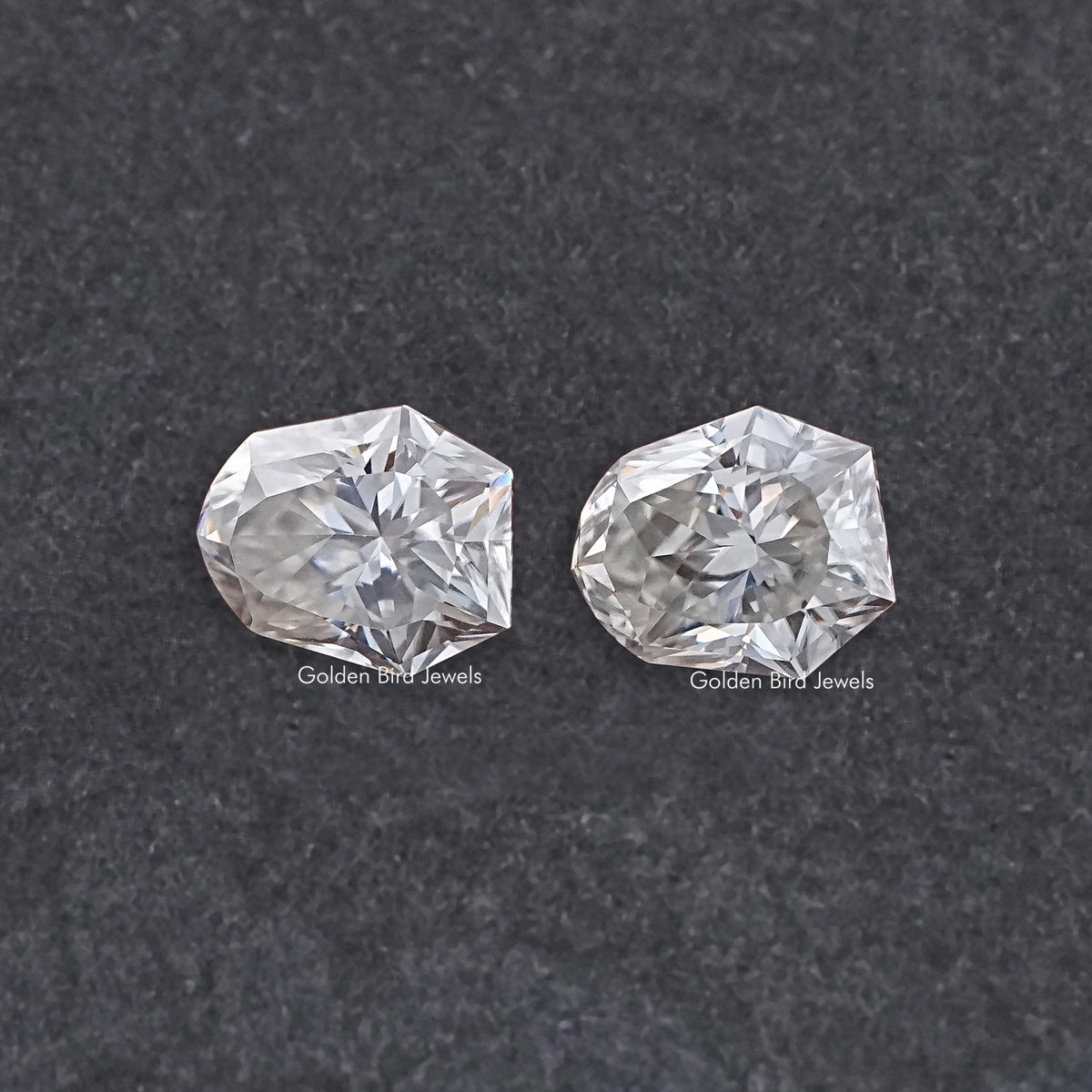 Shield-cut moissanite gemstones pair, clear faceted stones with matching shape