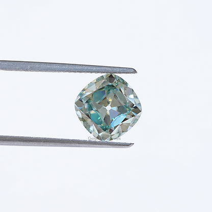 Light blue moissanite gemstone in silver tweezers, cushion old mine cut
