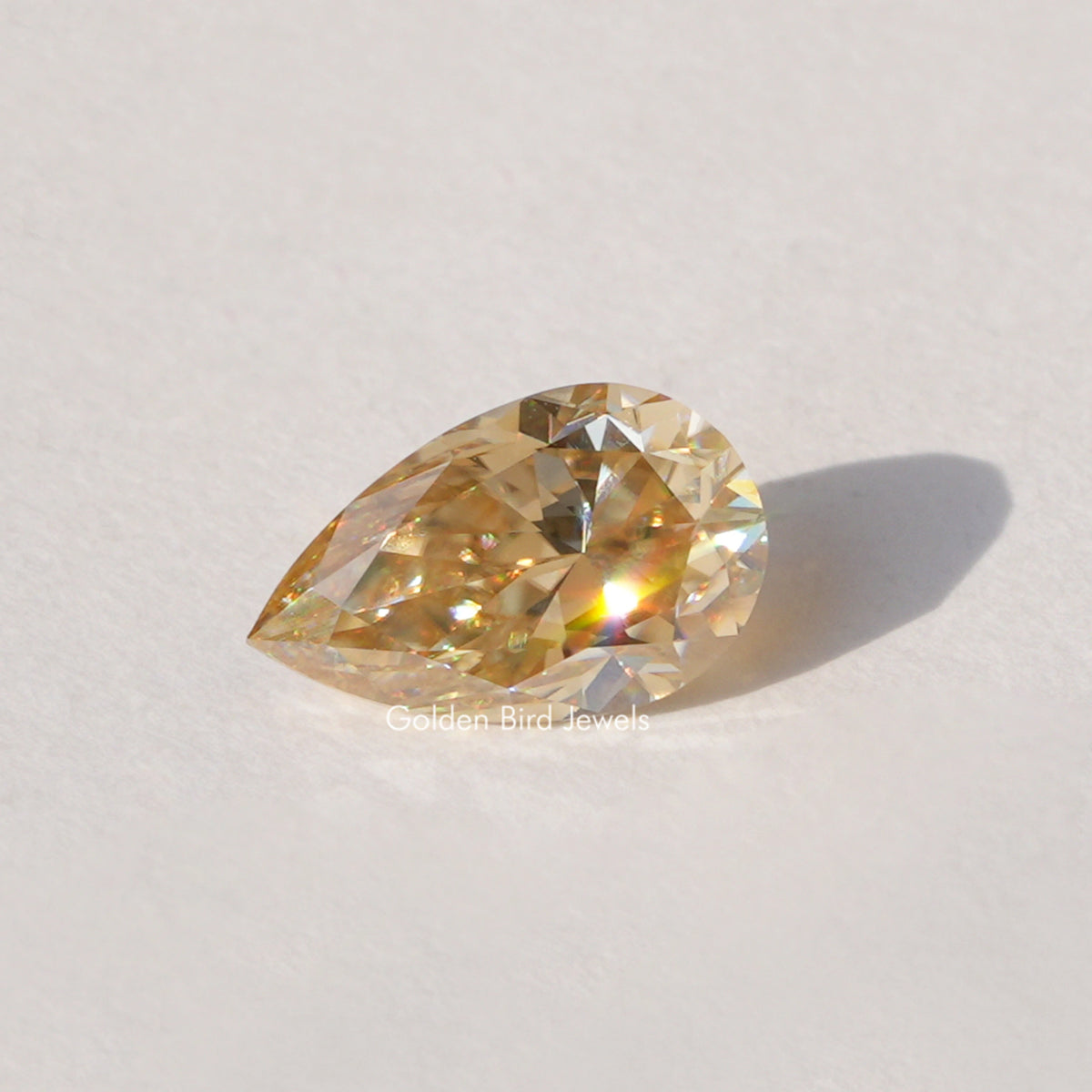 Pear-cut champagne moissanite loose stone, golden faceted sparkle.