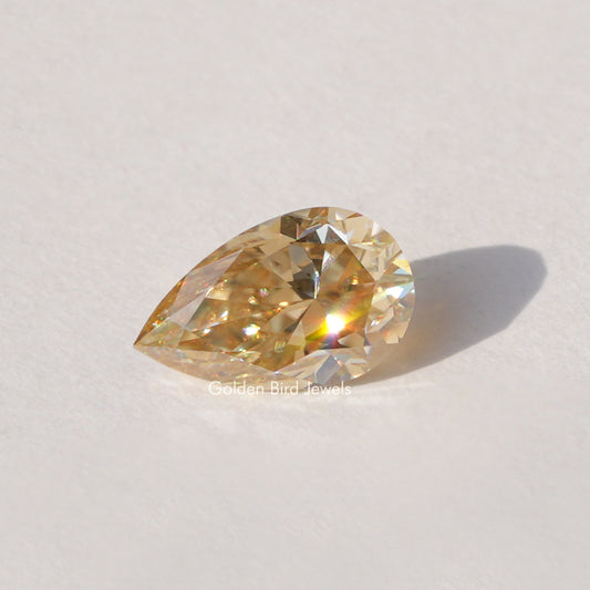 Pear-cut champagne moissanite loose stone, golden faceted sparkle.