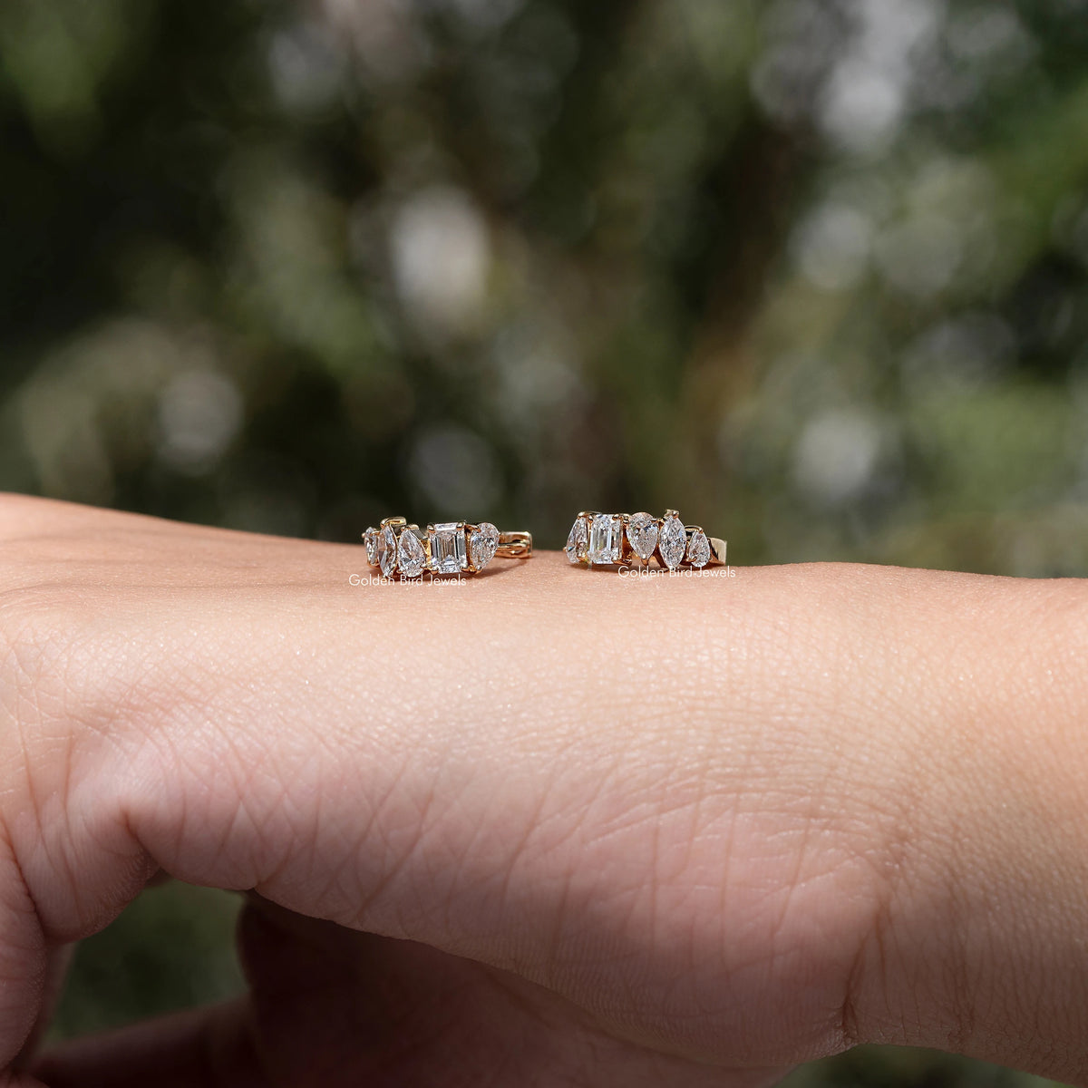 Pair of gold-tone huggie hoop earrings with multi-shaped lab diamonds on hand
