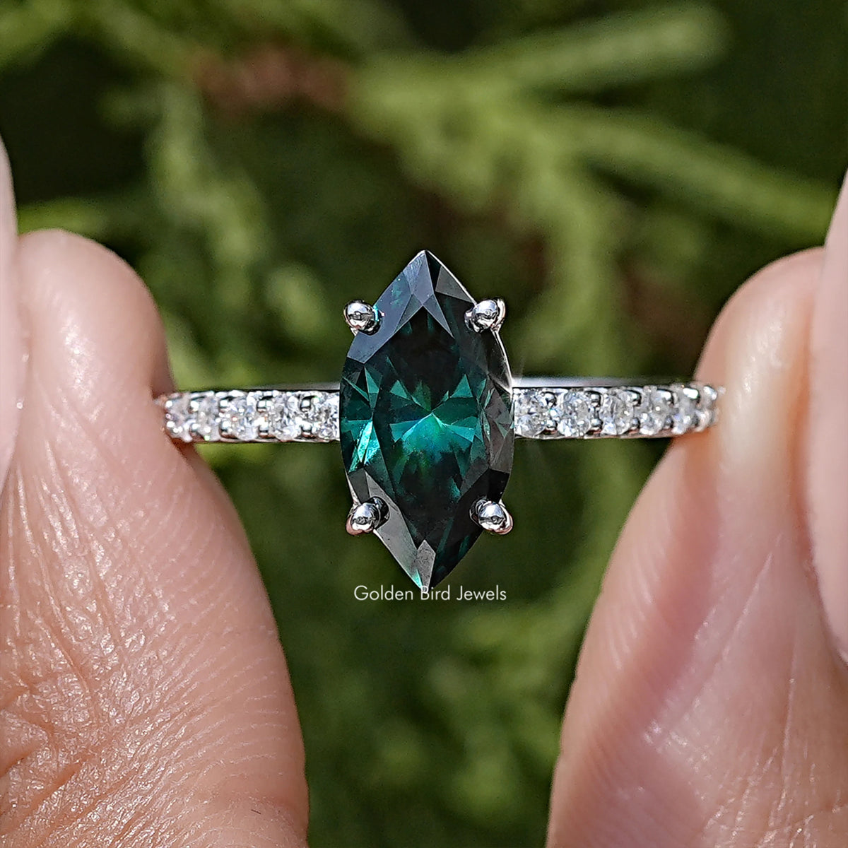 Marquise green moissanite center stone on sterling silver band with side sparkle accents.
