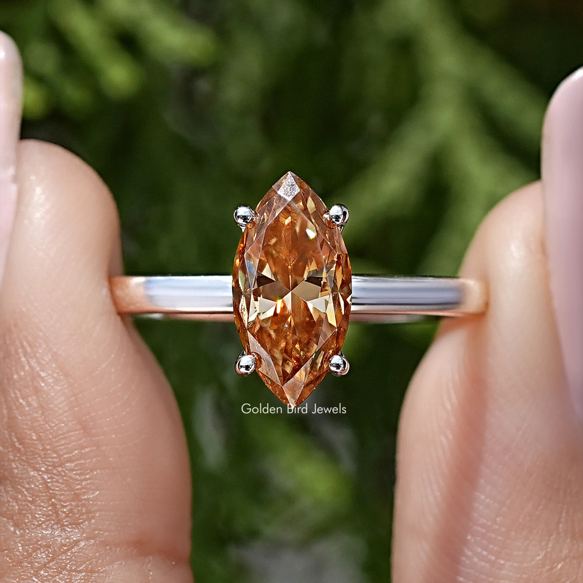 Close-up of silver ring with marquise-cut orange center and four round accents