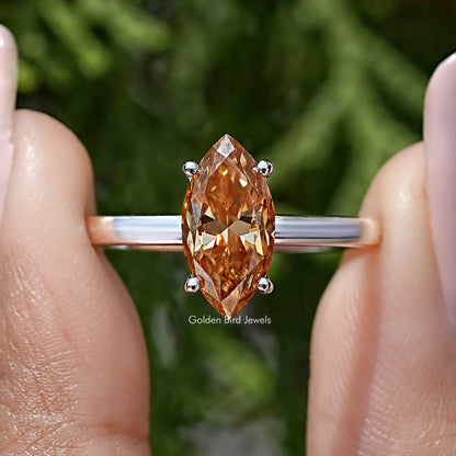 Close-up of silver ring with marquise-cut orange center and four round accents