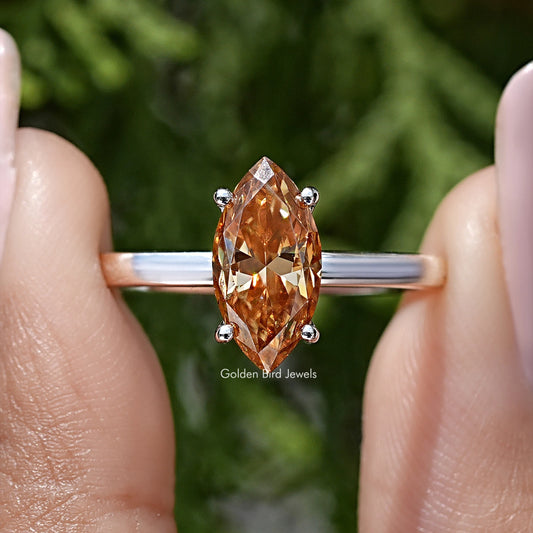 Close-up of silver ring with marquise-cut orange center and four round accents