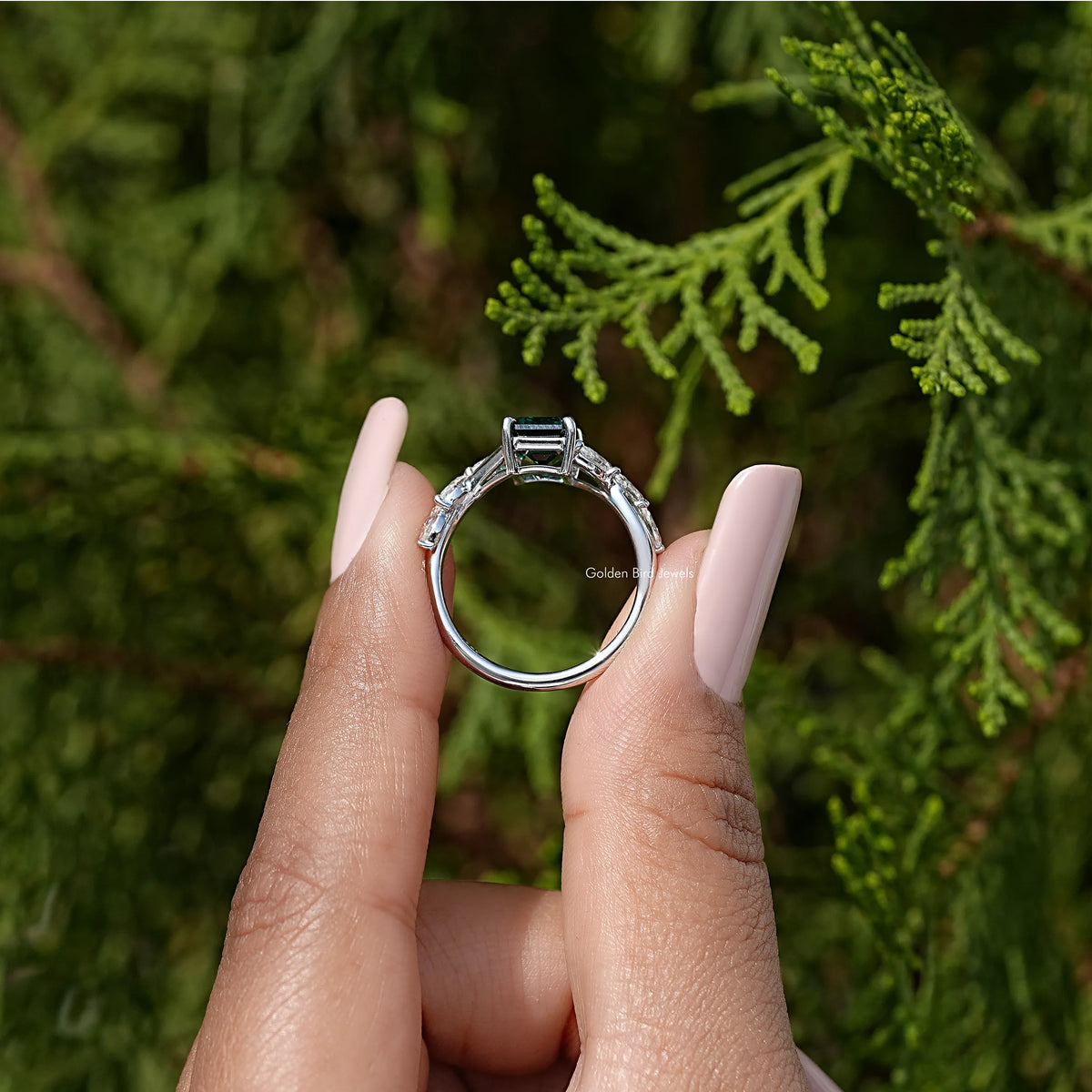 Sterling silver ring profile with green emerald-cut center stone.