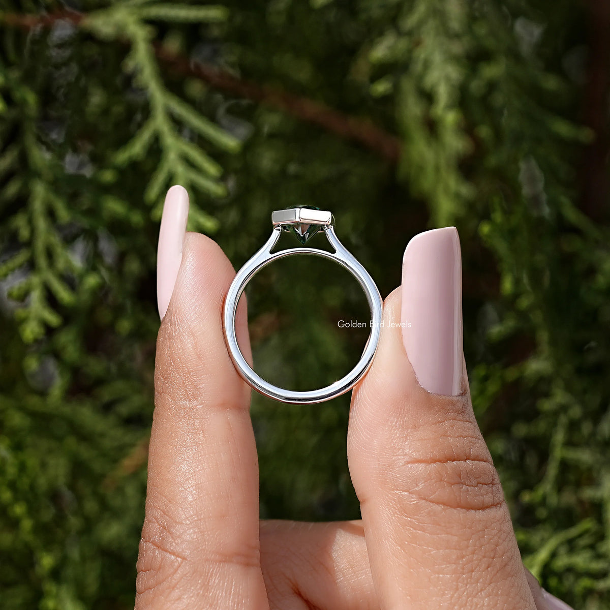 Sterling silver ring featuring a bezel-set green marquise stone viewed straight on