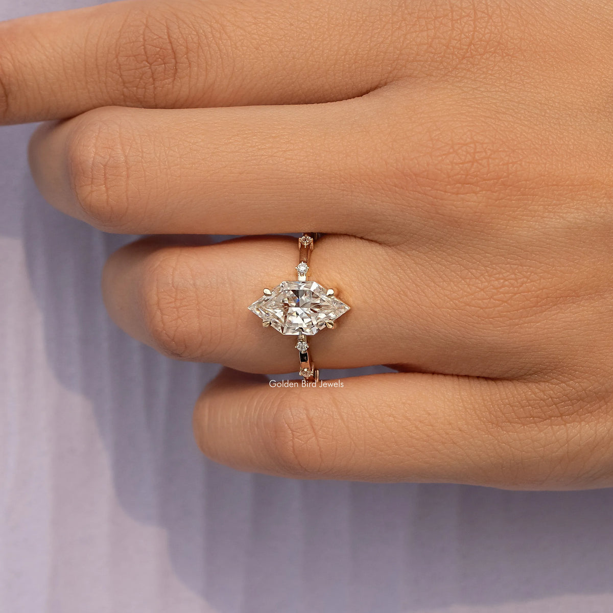 Gold-tone marquise moissanite ring on finger, showing center marquise and prong setting