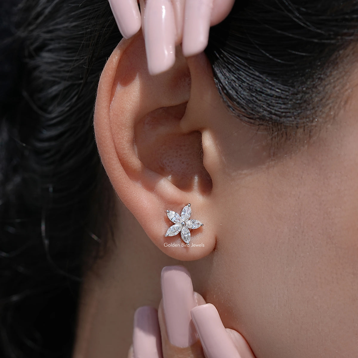 Marquise-cut diamond floral stud earrings close-up on ear with butterfly-like petals