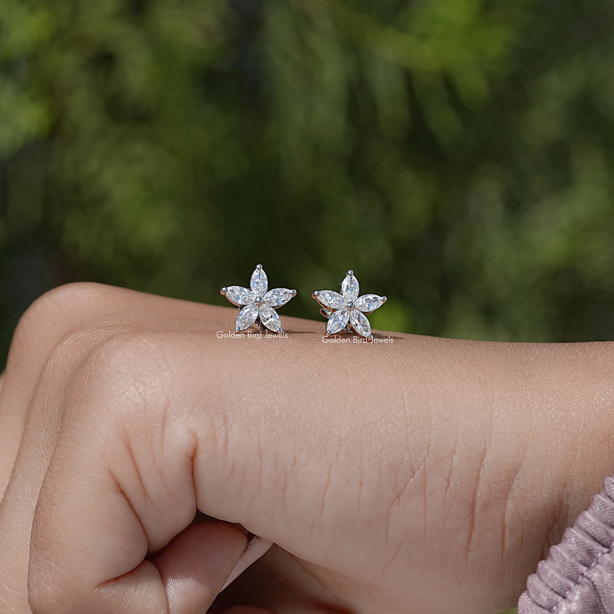 Marquise-cut diamond floral stud earrings on hand, flower shape with marquise stones