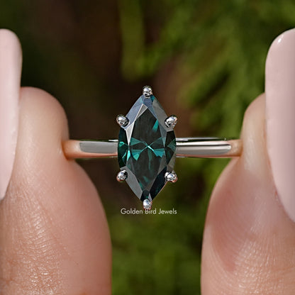 Close-up of silver solitaire ring with marquise teal gemstone and four prongs