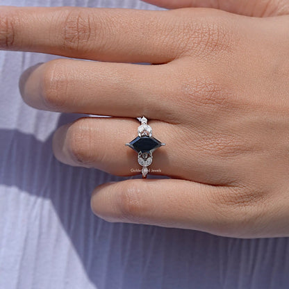 Silver ring on finger with marquise black center stone and clear leaf accents