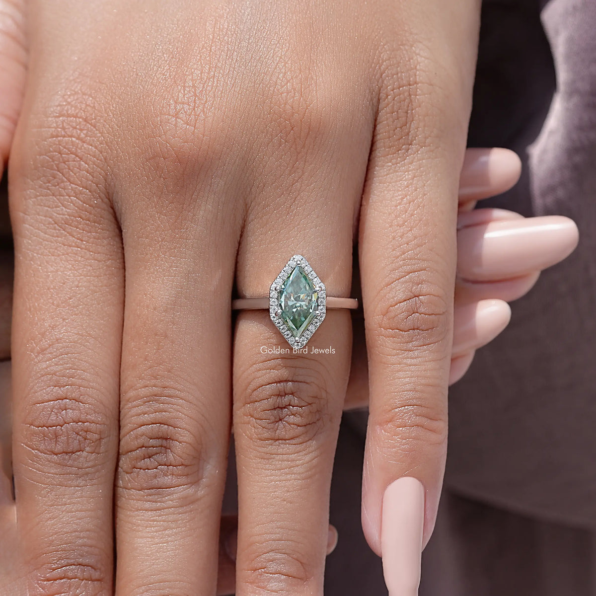 Sterling silver marquise moissanite halo wedding ring with green center stone on hand