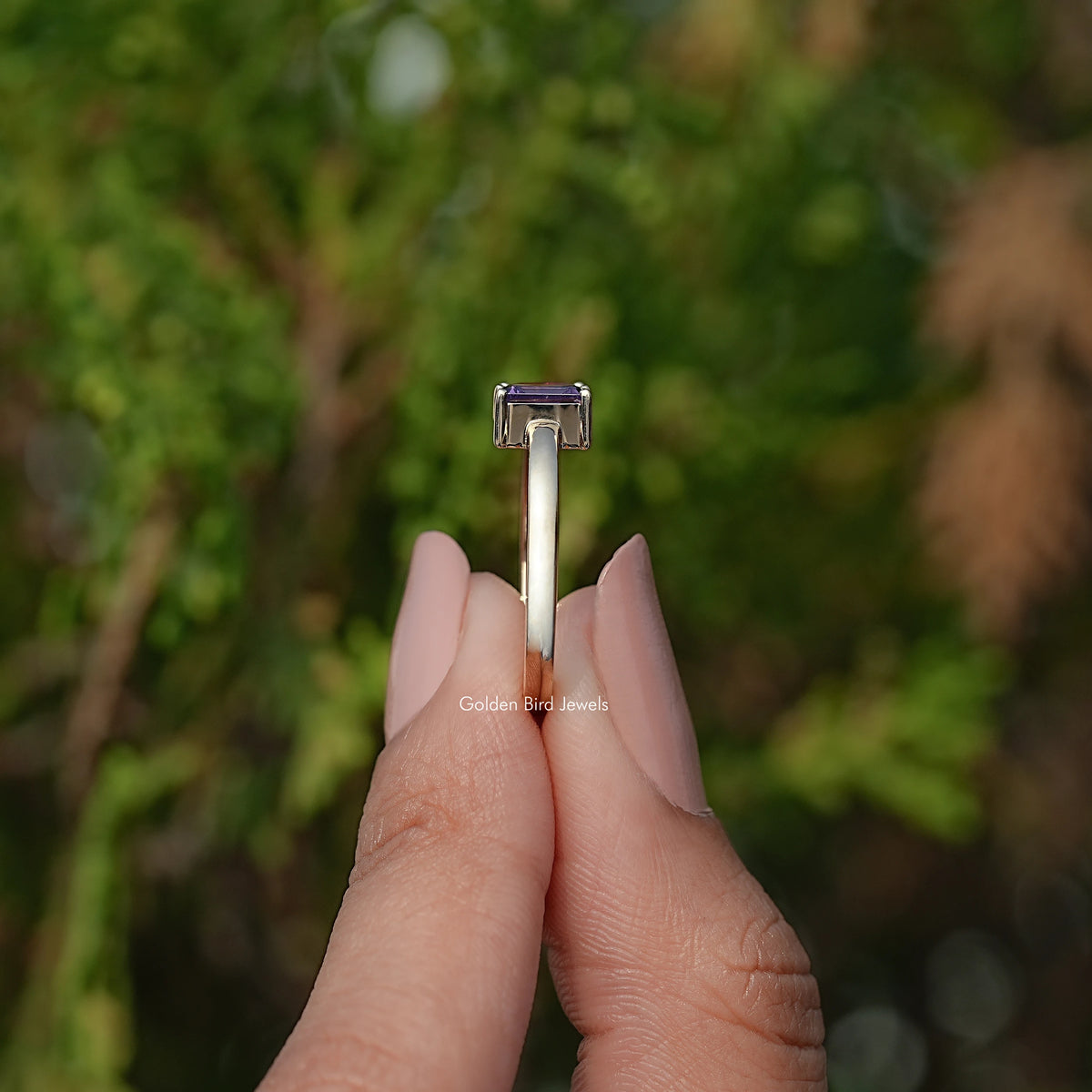 Open cuff ring underside view, showing prong-set emerald-cut dark blue stone