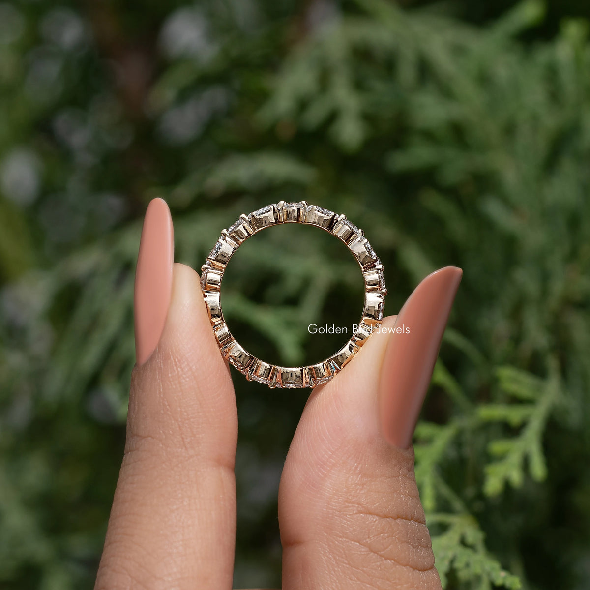 Lab-grown diamond wedding band with marquise and round stones, held on fingers