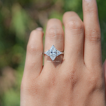 Three-stone moissanite ring on finger, marquise center with triangle side stones, silvertone.