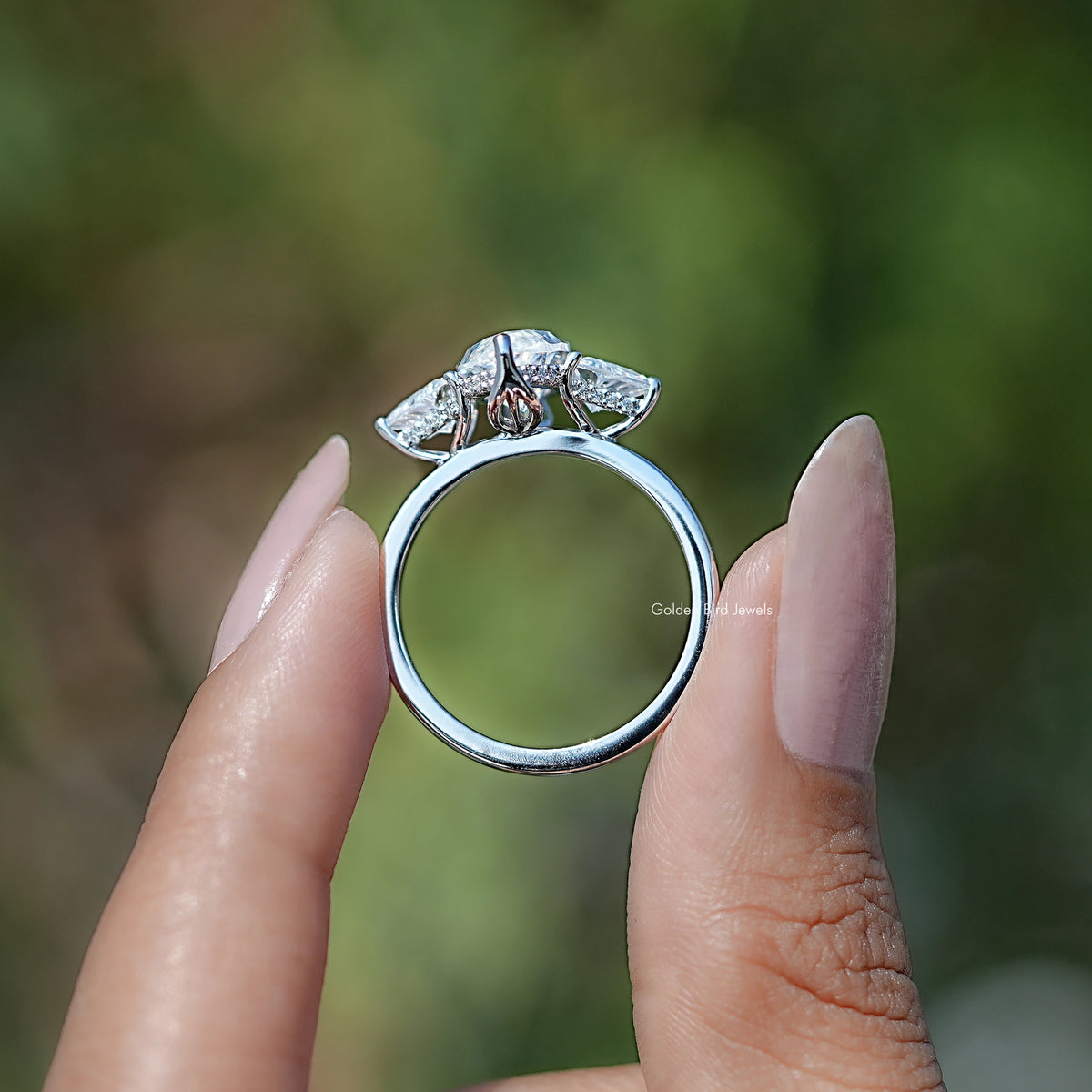 Three-stone moissanite ring from side view, marquise center with triangle accents, silvertone.